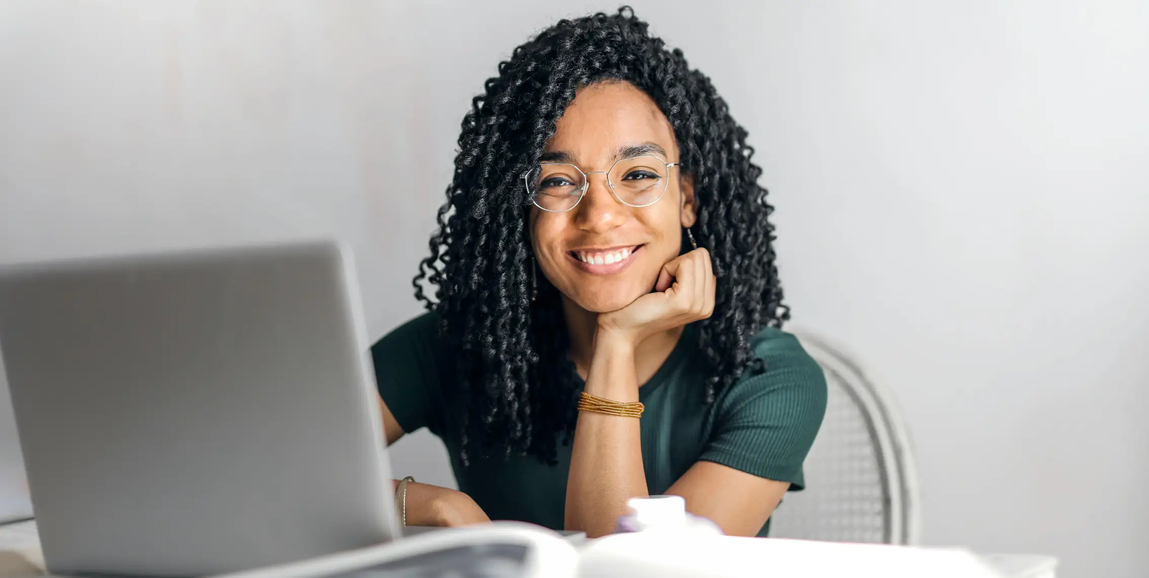 A female human girl working on a laptop and smiling in the camera